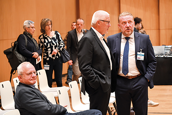 Teilnehmer eines medizinischen Fachkongresses im Gespräch, umgeben von Sitzreihen und weiteren Besucherinnen und Besuchern.